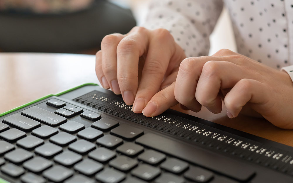 A picture of a person’s hands typing on a braille keyboard meant to signify an inclusive culture at work through accessible technology.