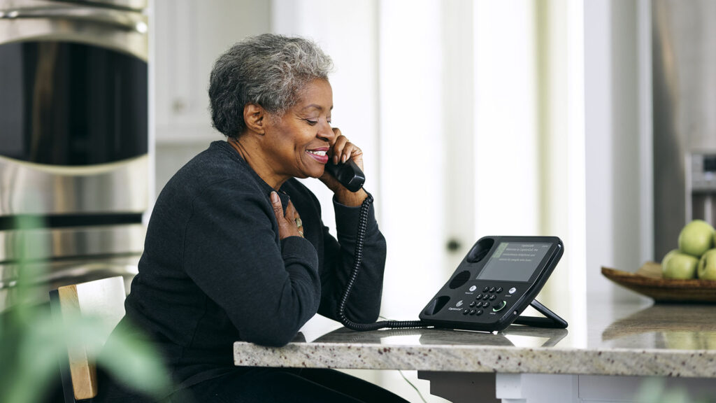 Senior woman talking on a captioned phone