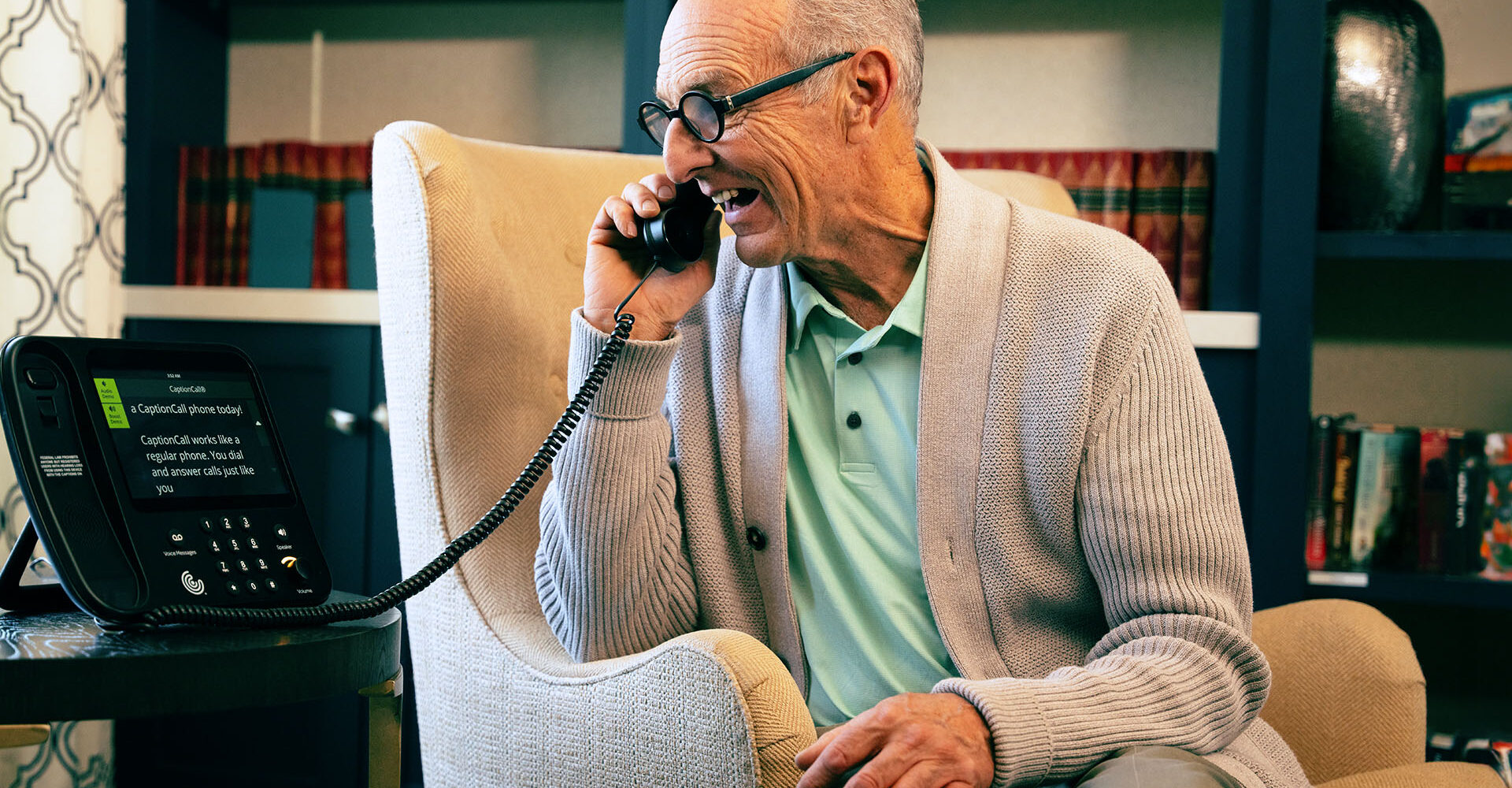 Older man using a CaptionCall phone to enjoy a phone call.