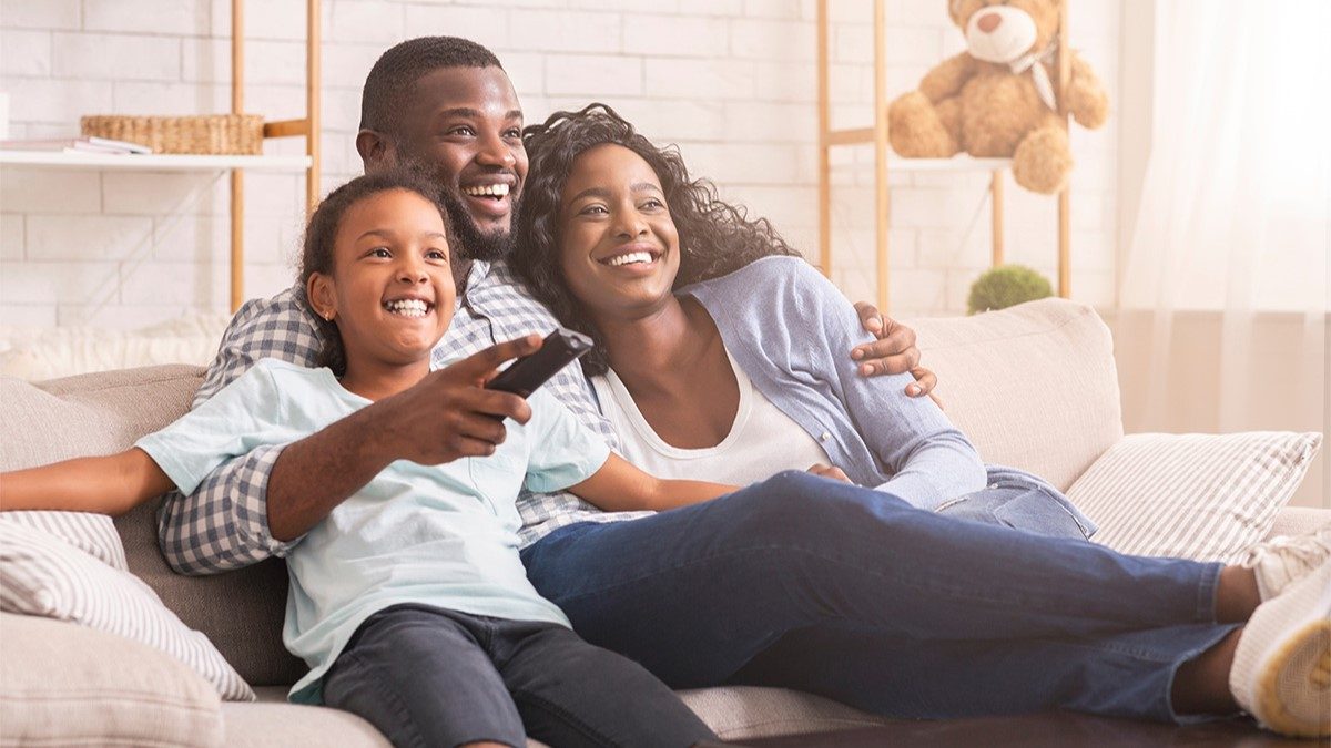 Mother, father and daughter on couch watching a movie with captions turned on